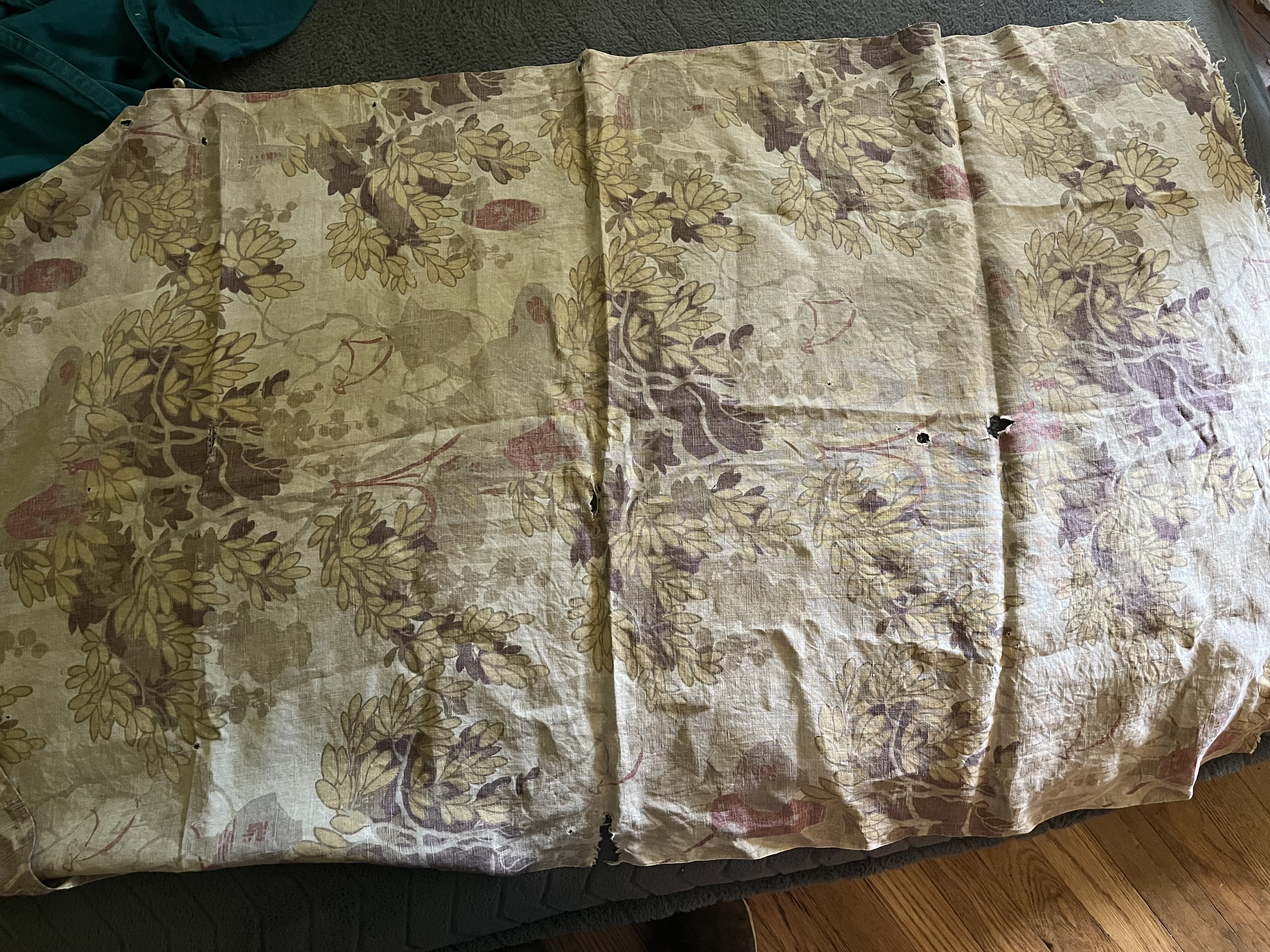 Crumpled beige fabric with some holes. There’s a print of vines and Asian-style lanterns in brown, taupe, red, and yellow.